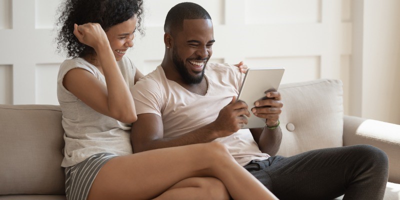 Husband and wife looking at tablet on a couch 