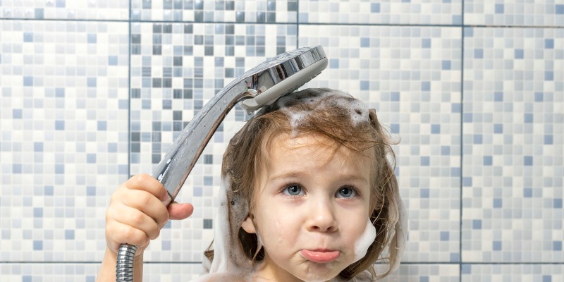 child holding shower faucet with no water.