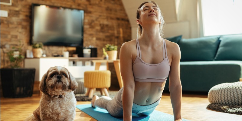 woman relaxing in house doing yoga with dog